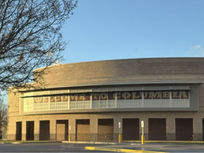 Brown building with banner that reads welcome to Columbia, background is a blue sky