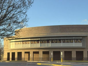 Brown building with banner that reads welcome to Columbia, background is a blue sky