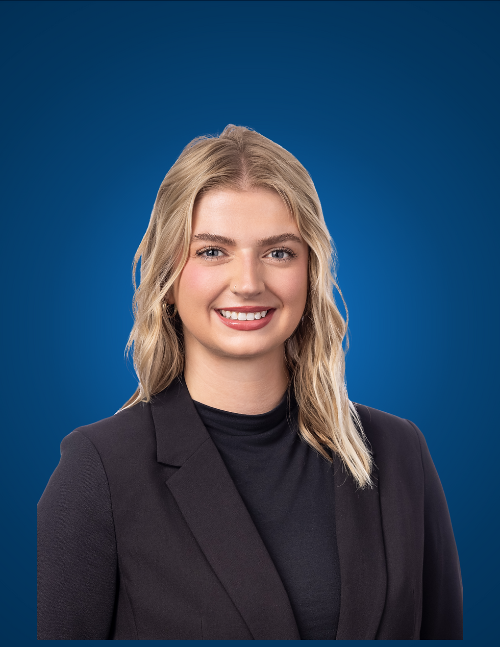 Smiling blonde woman in a black blazer posed against a plain blue studio background.