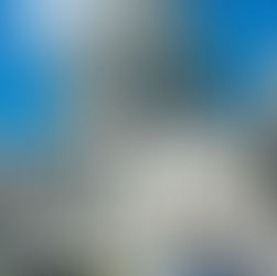 Man in navy suit and yellow striped tie standing in front of the United States Capitol building under a clear blue sky in Washington, D.C.