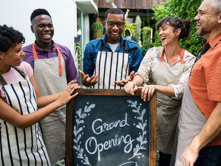 Group of happy, smiling people with a 'Grand Opening' sign