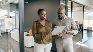 Two business people reviewing documents on a tablet