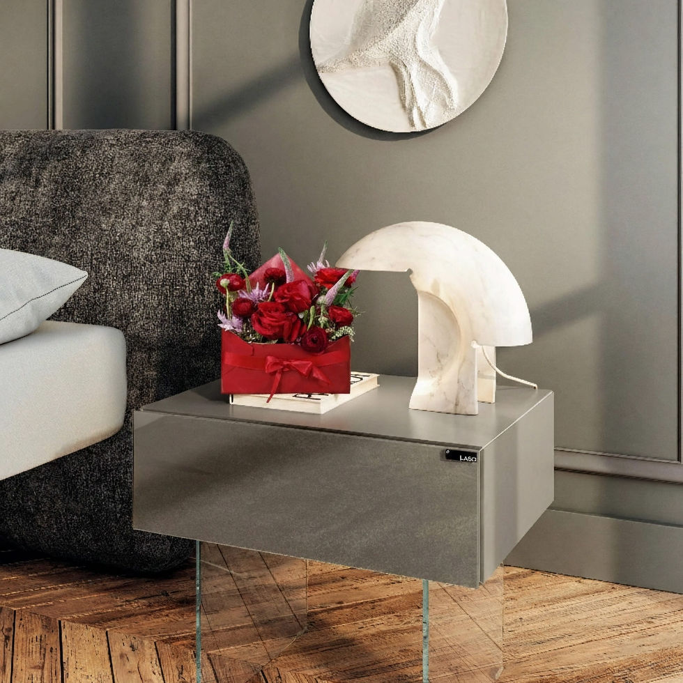 Lettre fleurie rouge dans une enveloppe décorative posée sur une table de chevet moderne, adossée à une lampe en marbre.