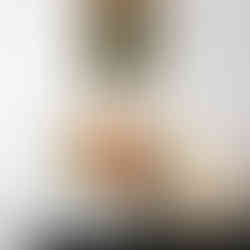 Bouquet Soleil de Jurançon posé sur un meuble en marbre vert, dans un vase blanc texturé, accompagné d’une lampe design