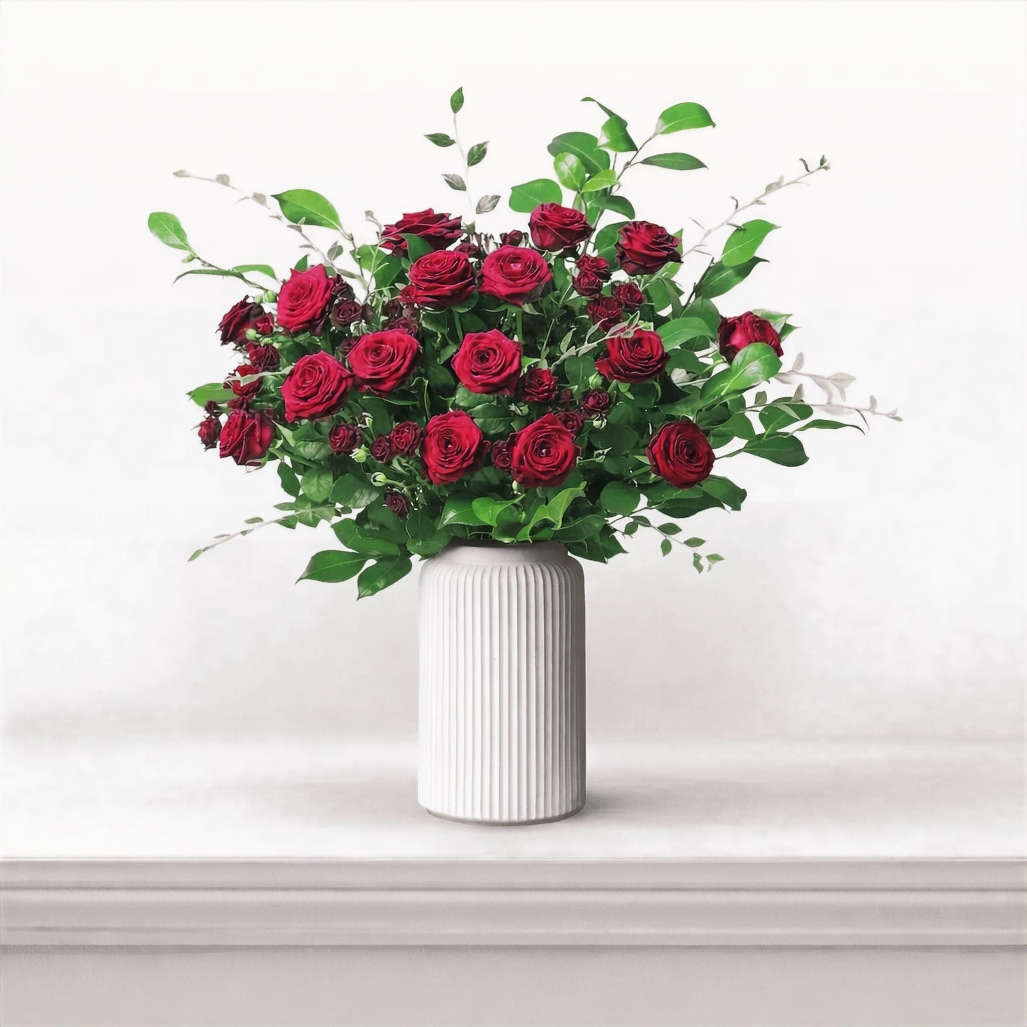 Bouquet de roses rouges dans un vase gris sur table d’appoint, ambiance cosy et élégante – création florale Or Végétal