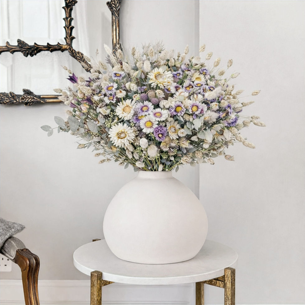 Bouquet de fleurs séchées pastel dans vase en grès blanc sur table basse blanche