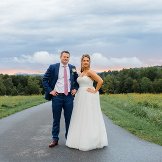 Just-married couple standing in front of a vibrant rainbow sky after the rain, creating a picturesque wedding moment