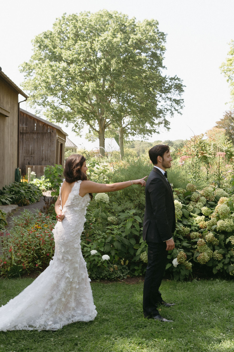 bride tapping groom’s shoulder for first look in outdoor wedding setting