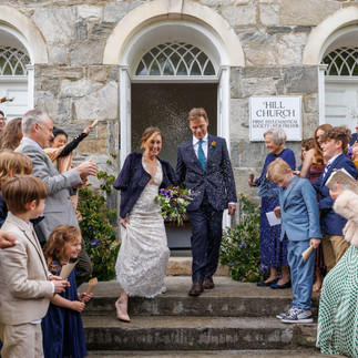 Just-married couple walking out of the ceremony under a rice shower, celebrating their wedding