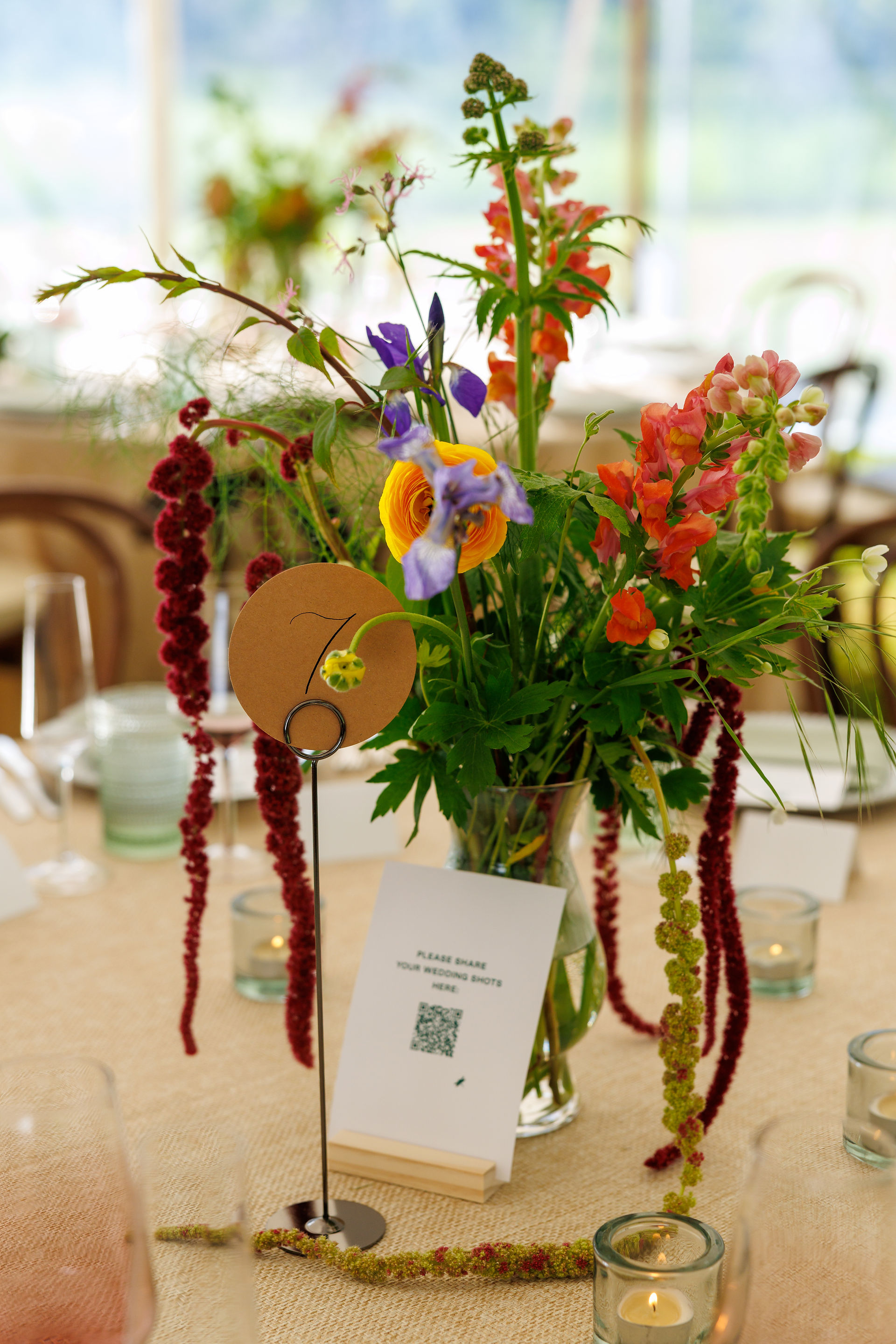 QR code for guests to share photos, next to a dark floral centerpiece with meadow vibes, a 2026 wedding trend