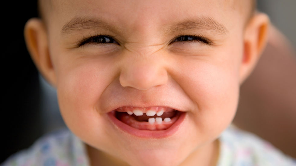 young child smiling with funny grin and showing lots of baby teeth with some still to come through