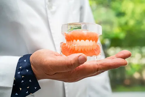 compressed_denture-dentist-holding-dental-teeth-model-to-stu-2026-03-20-00-10-57-utc.webp