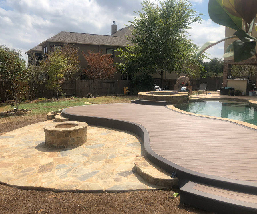 Curved custom deck surrounding a pool and stone patio