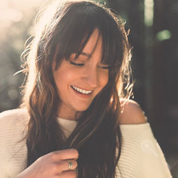 Portrait of brunette female model smiling while backlit by sunlight at sunset in a forest at Tyn-Y-Coed woods near Cardiff