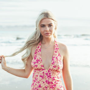 Portrait of blonde female model pulling her hair while looking at the camera and wearing summer dress on the beach at Ogmore-by-Sea in the Vale of Glamorgan