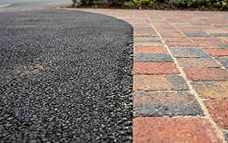 Close up of brindle paving edge on tarmac driveway.