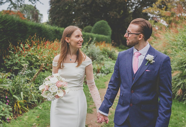 Bride and groom holding hands looking at each other during walk on wedding day through Insole Court gardens in Cardiff