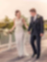Bride and groom walking hand in hand looking at each other smiling during sunset