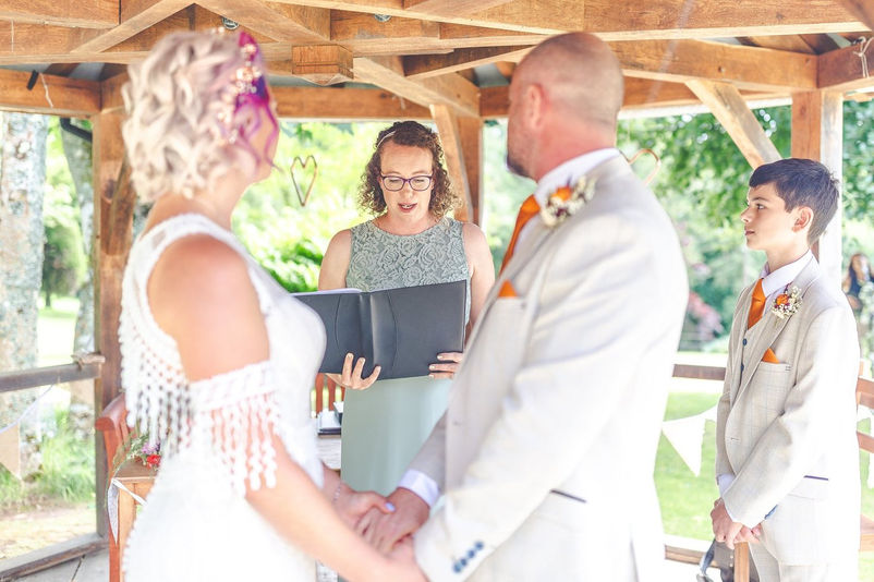 Bride and groom holding hands during wedding ceremony otuside at Hilton Court Gardens in Pembrokeshire