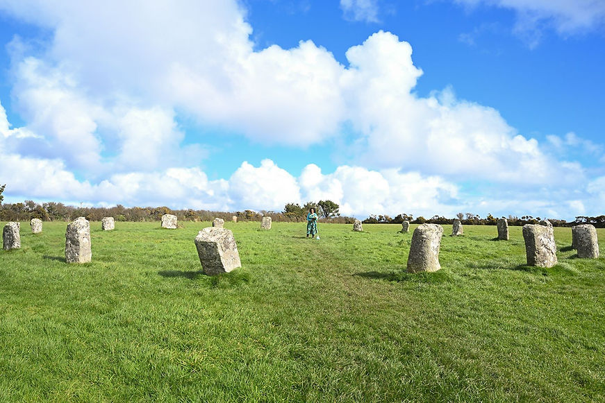 Woman standing in a field surrounded by stone pillars