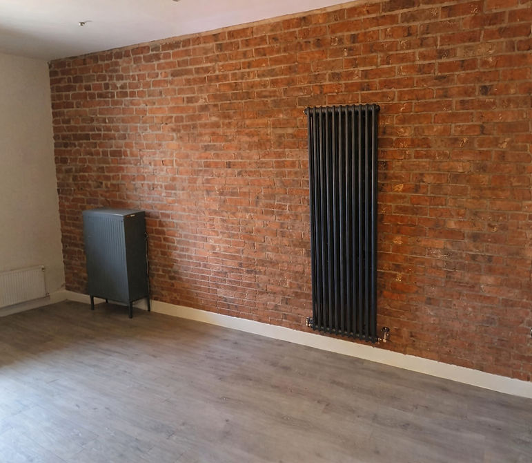 Tall black radiator against a red brick wall