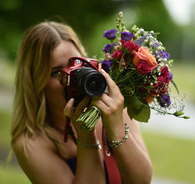 Woman taking a photograph holding a colourful bouquet