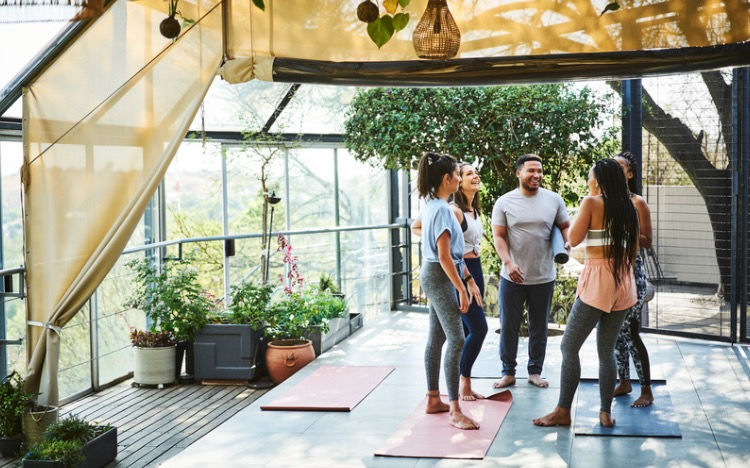 Five people gathered around yoga mats talking