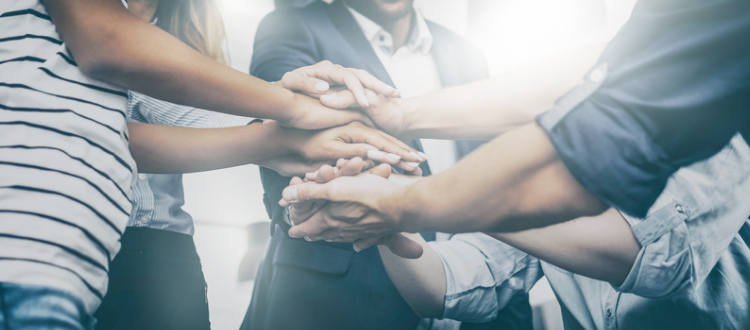 Five people stacking their hands on top of each others'