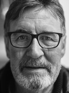 Charakterkopf in Schwarz-Weiß: älterer Mann mit dunkler Brille und grauem Bart, direkter Blick