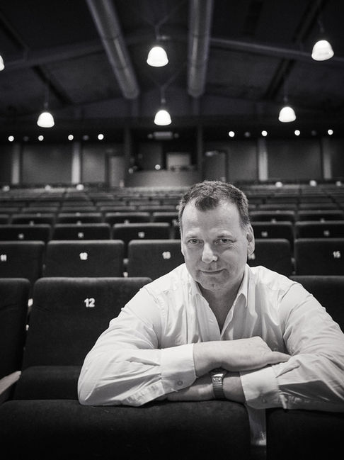 Mann im weißen Hemd sitzt allein in einem leeren Theatersaal, Schwarz-Weiß-Aufnahme
