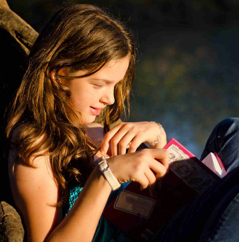 A girl reading a book in what looks like a dark background. 