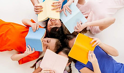 a multi ethnic group of elementary age children lying in a circle and reading books_edited