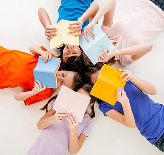 a multi ethnic group of elementary age children lying in a circle and reading books_edited