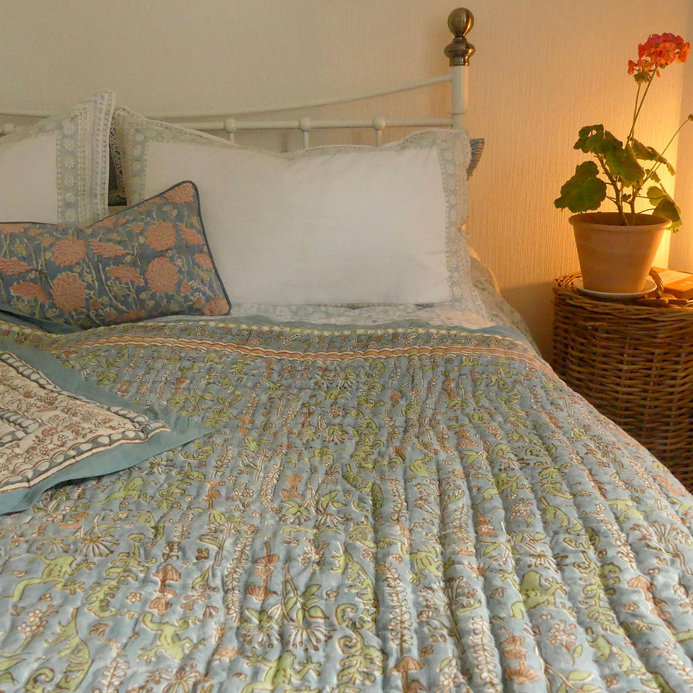 Thumbnail: Dressed bed with printed quilt and bedside table with Geranium flowers
