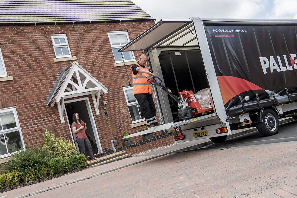 A man in a hi-vis jacket delivering a pallet to a residental house. The man is stood in the back of a Pall-Ex vehicle with a pump truck