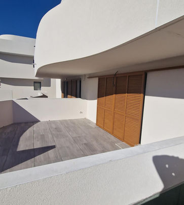 Terrasse moderne aux lignes courbes et volets en bois.