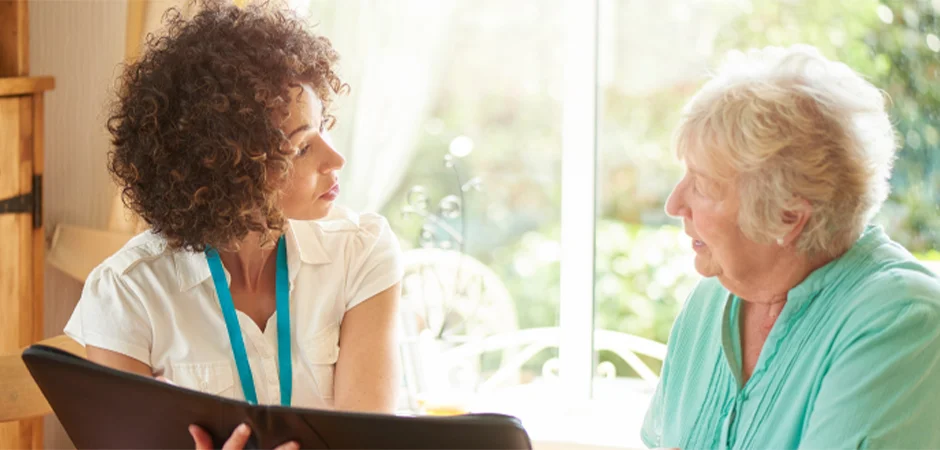 A healthcare professional engages in a thoughtful conversation with an elderly woman, offering guidance and support in a bright and welcoming environment.