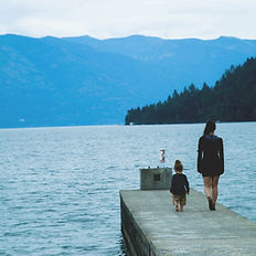 A woman and a child walking along a pier towards the end of the pier. There are mountains and a forest in the back ground. This represents the healing of the inner child. Our inner child always walks along side us waiting to be acknowledged and integrated back within ourselves so that we can come into wholeness of ourselves.
