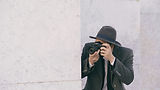 Private investigator in fedora photographing surveillance target