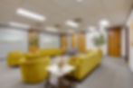 Waiting room with yellow seating and numbered doors