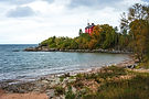 Red house on a point surrounded by autumn trees and a rocky bay