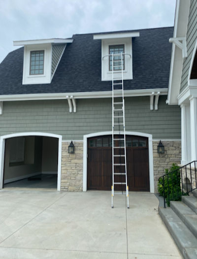 Large house, two-car garage, green siding and dark roof