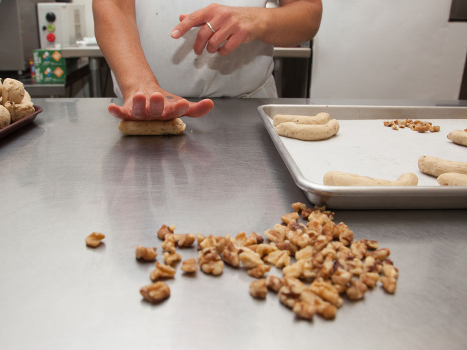 Baker presses dough, walnuts, and cookie making at Cookie Time Bakery.