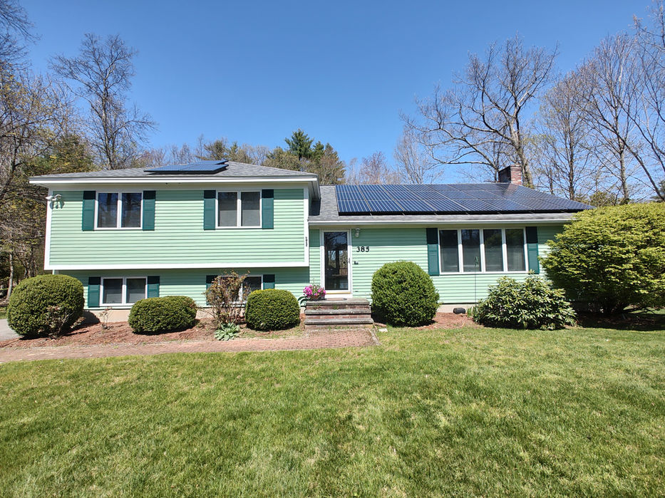 Light green house with solar panels on roof, green lawn front