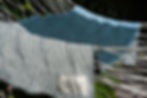 Textured throw blanket with teal and silver woven pattern draped over outdoor chair.