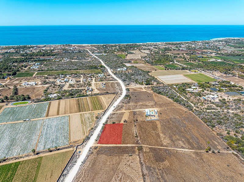 Aerial view of a coastal property with fields and the sea in the background