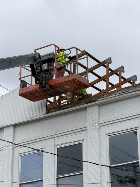 Construction worker on cherry picker demolishing metal roof frame