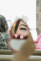 Reflet de l'œil maquillé de la mariée dans un petit miroir