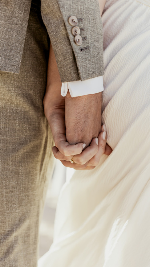 Mains enlacées des mariés lors de leur mariage sur la plage