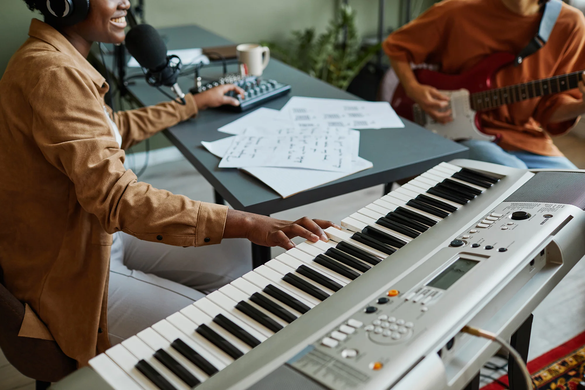 closeup-of-black-young-woman-pressing-piano-keys-while-composing-music-with-band-of-young-